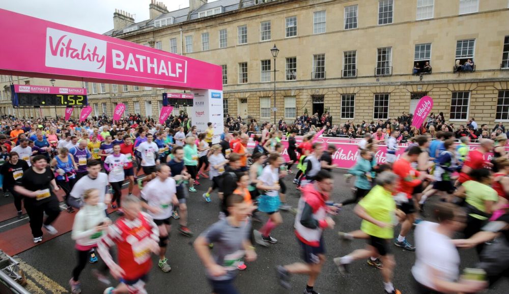 Group of runners running through start gate detailing 'Vitality Bath Half'